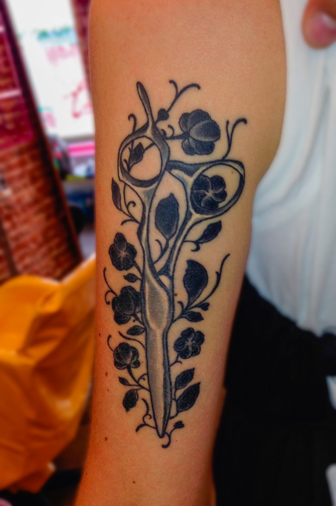 Arm Tattoo einer Mizutani Schere Acro Z-1 umhüllt in Blumen