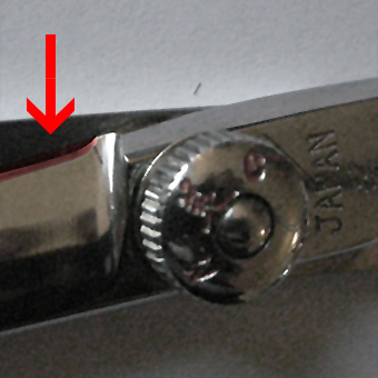 Roter Pfeil zeigt auf die stumpfe und beschädigte Klinge einer Mizutani Schere als Illustration der Gefahren durch einen externen Schleifservice