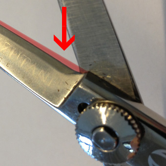 Roter Pfeil zeigt auf die stumpfe Klinge einer Mizutani Schere als Illustration der Gefahren durch einen externen Schleifservice