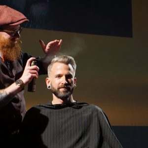 Mizutani Europe Barber Seminar 2019 Live Präsentation eines Haarschnitts Barber sprüht Haarmittel auf die Haare des Kunden